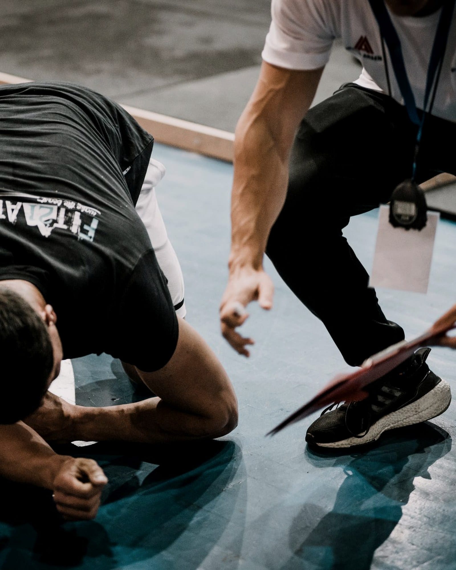 A coach holds a resistance band looped around a client's foot during a floor exercise