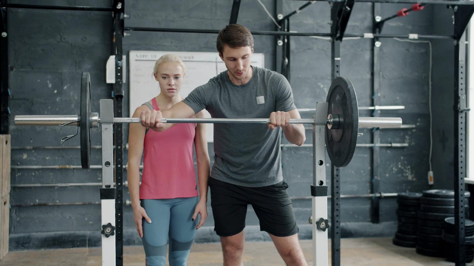 A personal trainer coaches a client through a session in a gym
